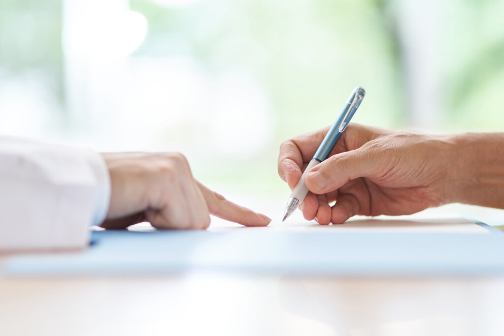 Person signing a contract with clinician at desk